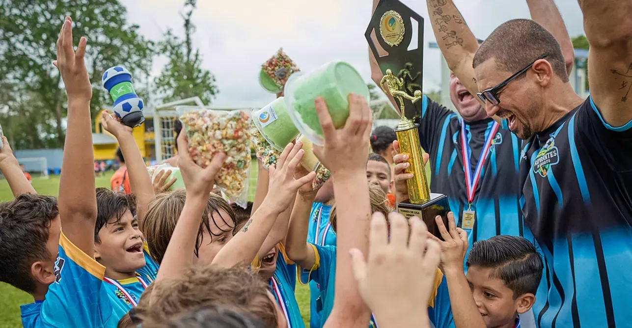 Niños y entrenadores de AFAG celebran con un trofeo, medallas y golosinas en alto